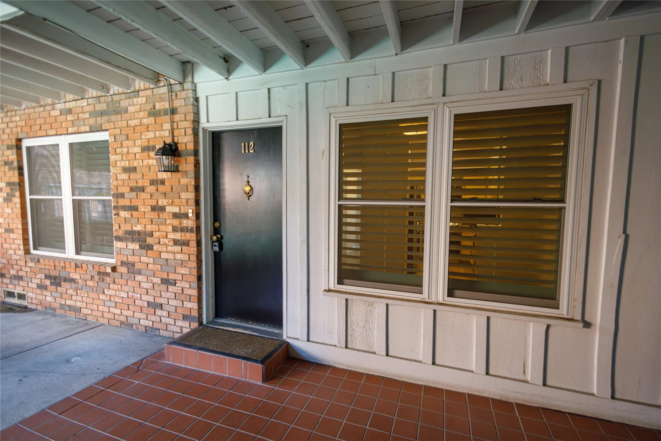 Brick and siding exterior with a tiled entry, dark entry door, and exterior lighting