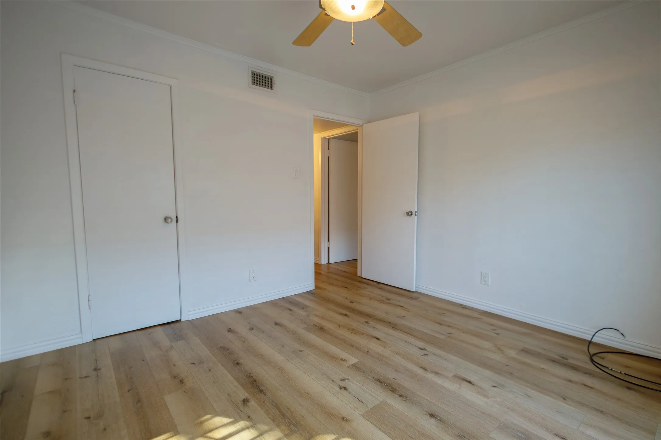 Wood-finish flooring, white walls, white doors, and a ceiling fan