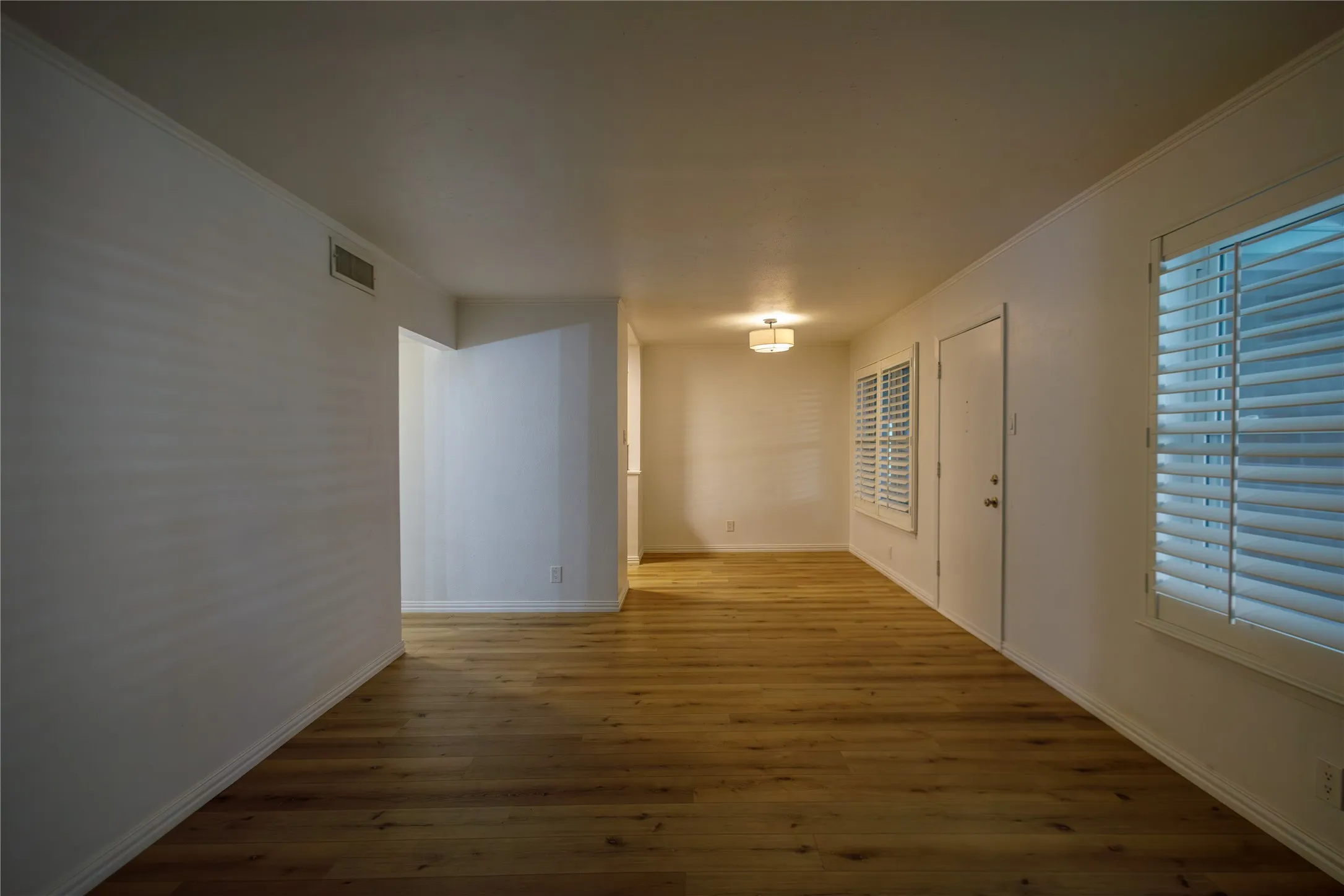 Wood-finish flooring, white walls, and a contemporary flush-mount light fixture