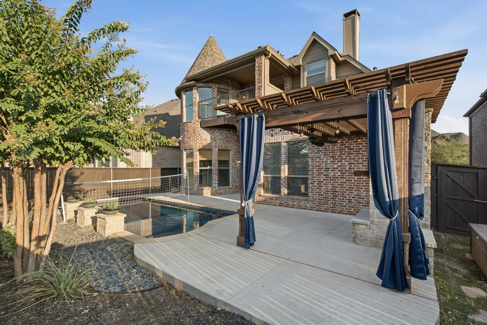 Brick exterior with turret, outdoor pergola, integrated pool, and a second-story balcony