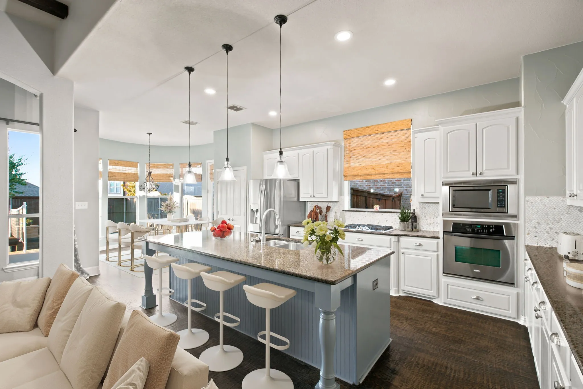 Kitchen featuring a center island with granite countertop, white cabinetry, stainless steel built-in appliances, and wood-finish flooring.  Virtually staged