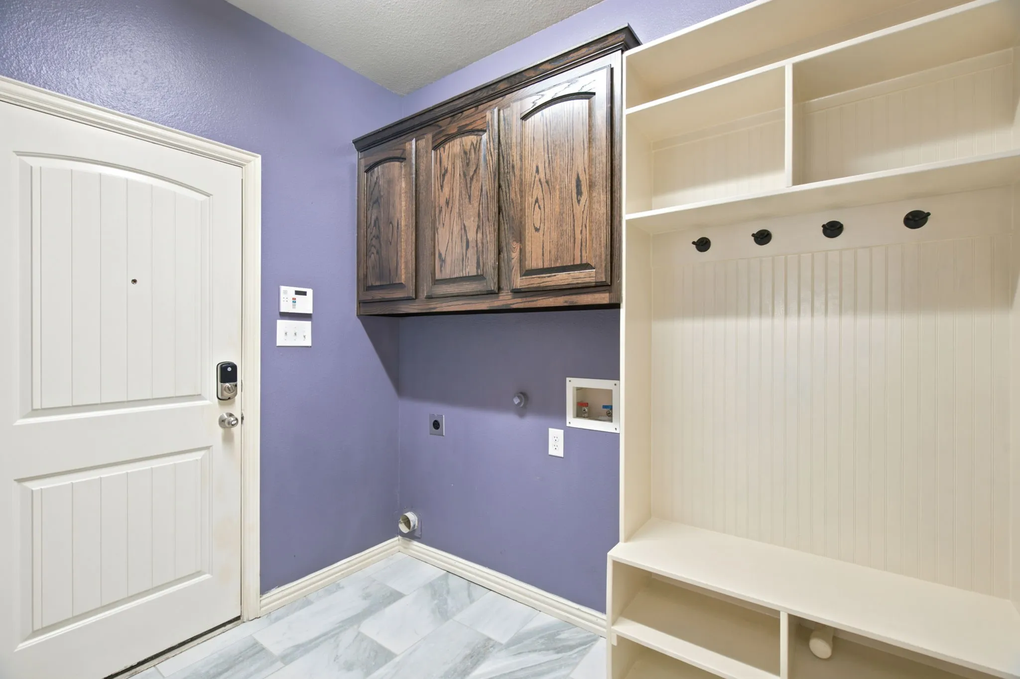 Built-in storage solutions, wood-finish cabinetry, light wood-look flooring, and a white paneled door