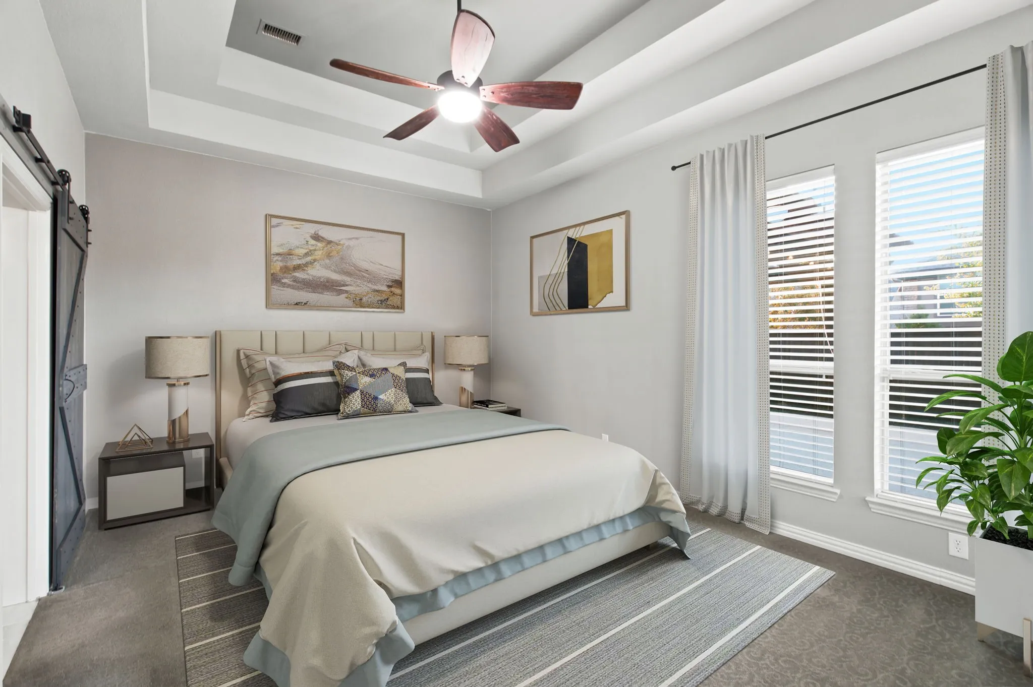 Tray ceiling with a ceiling fan, dual windows with blinds, and a barn door entry.  Virtually staged