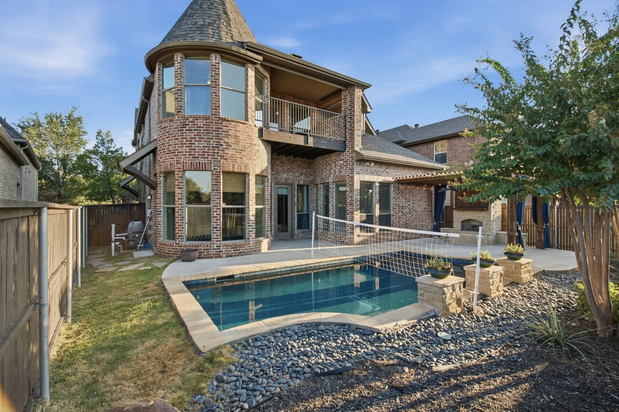 Brick exterior with a turret, private balcony, and patio with an outdoor fireplace