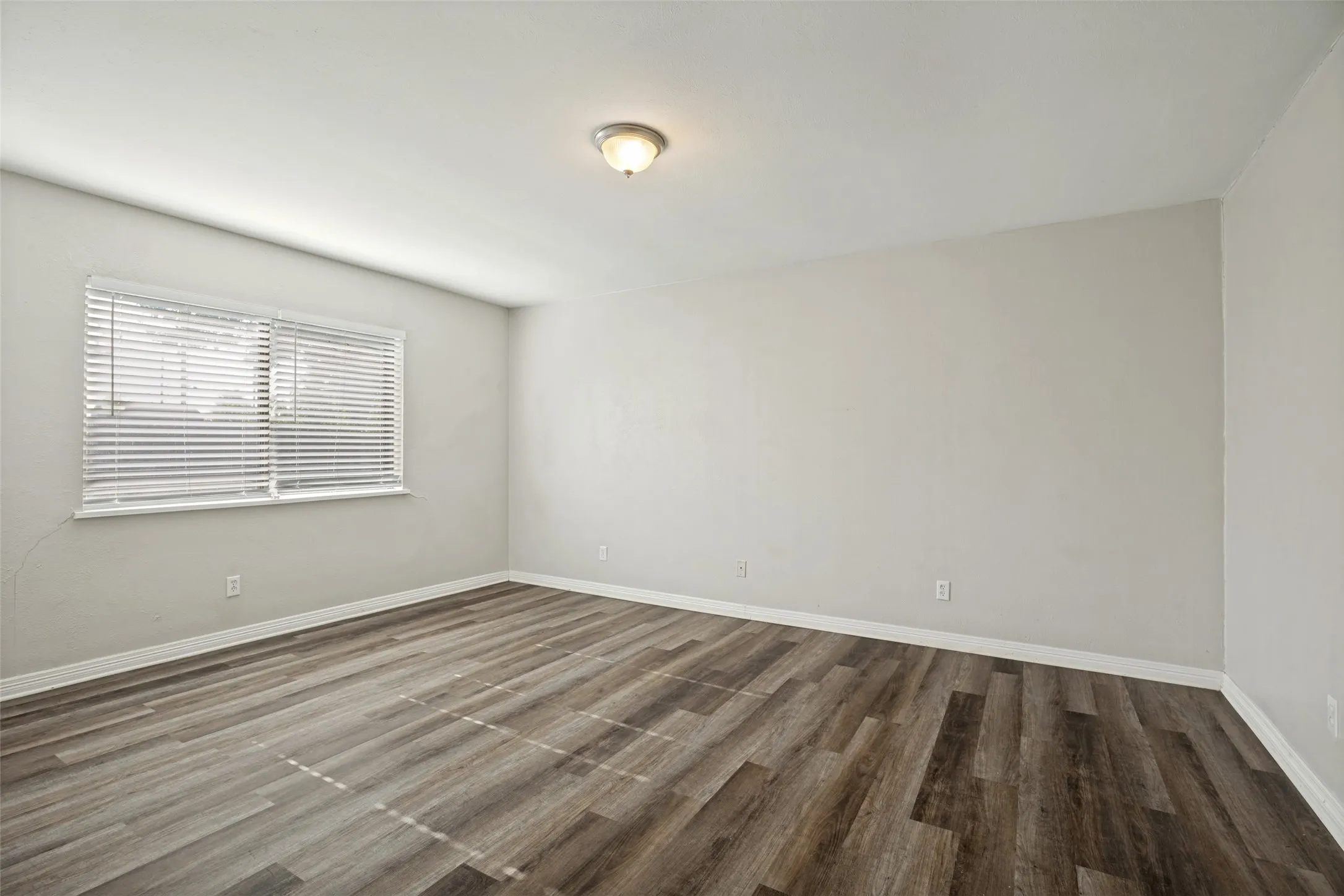 Wood-finish flooring, neutral wall paint, overhead flush-mount lighting.