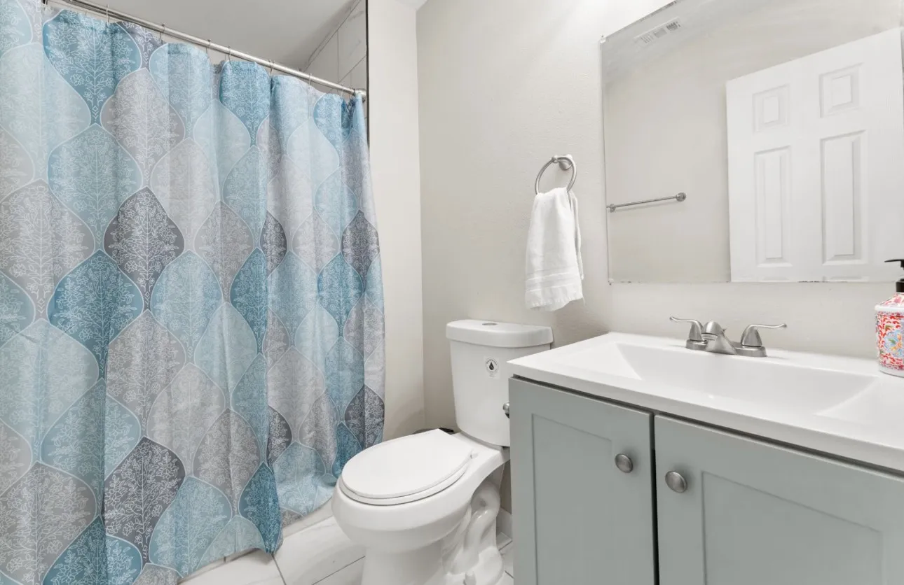 Light gray vanity with brushed nickel hardware, integrated sink, and wall-mounted mirror