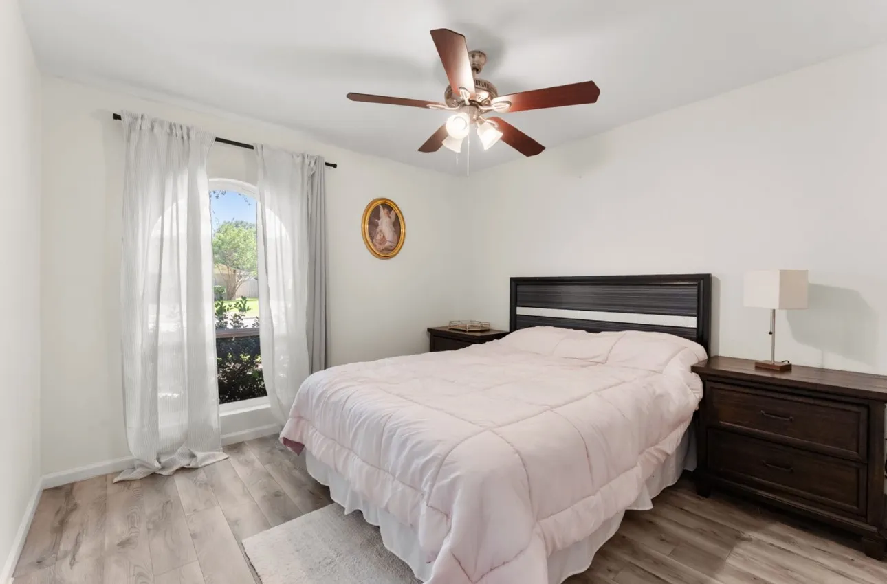 Wood-finish flooring with an arched window and a ceiling fan with light fixture
