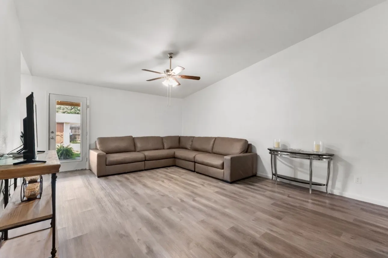 Vaulted ceilings, wood-finish flooring, ceiling fan, and a glass-paneled exterior door
