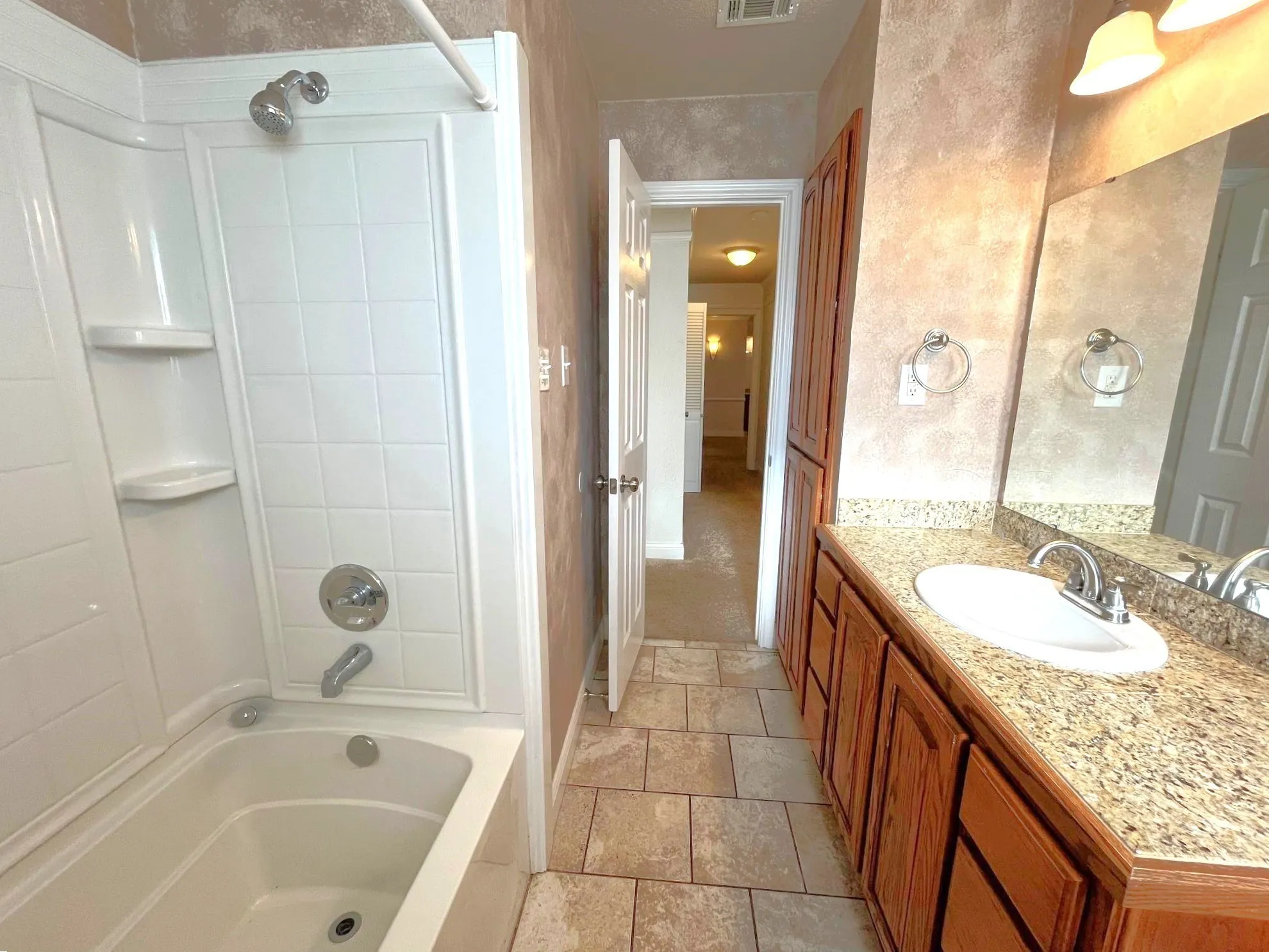 Bathroom featuring a vanity with an integrated sink, a built-in bathtub with shower, and tile flooring