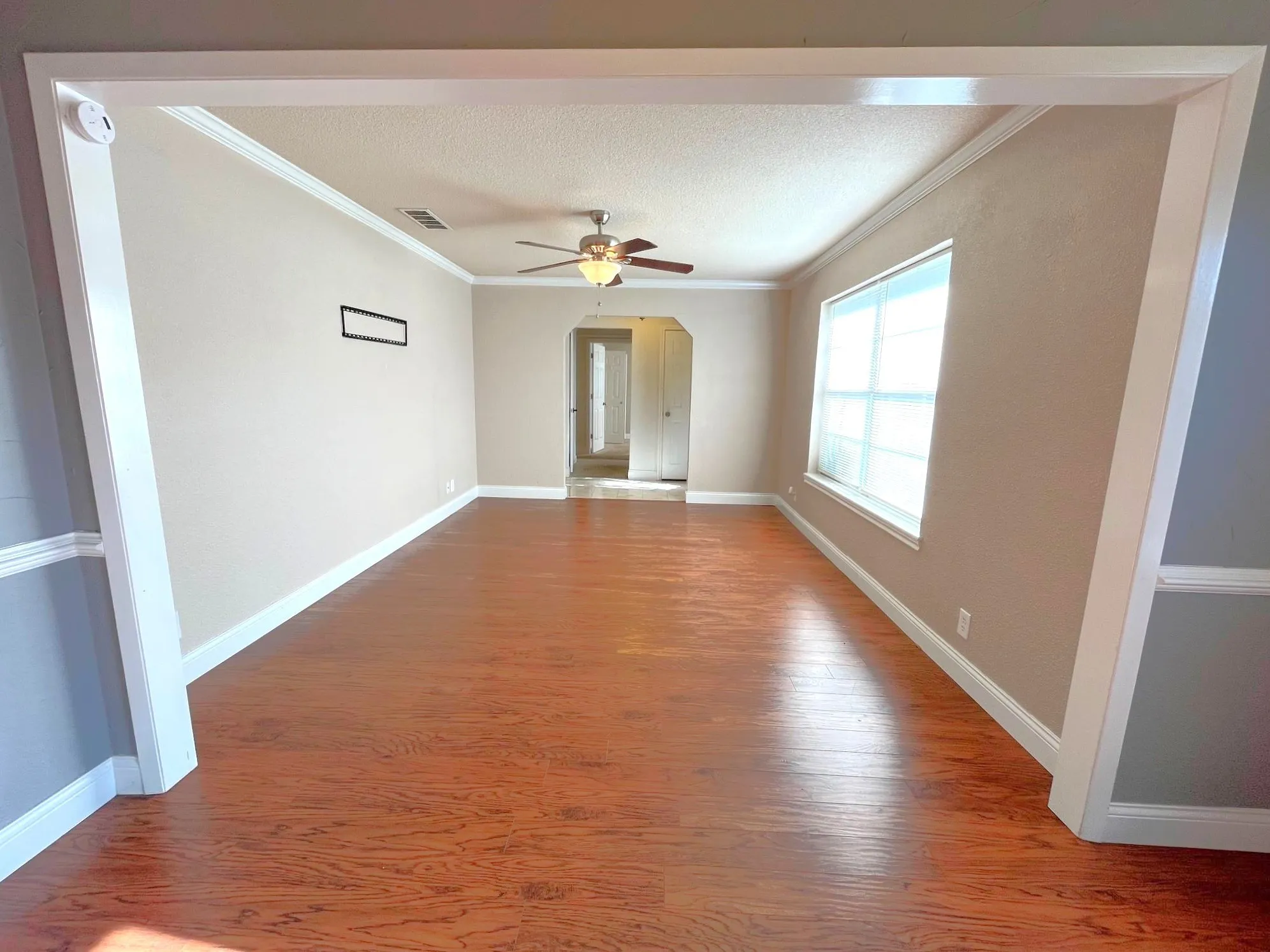 Wood-style flooring , ceiling fan with integrated lighting, window with blinds, and crown molding