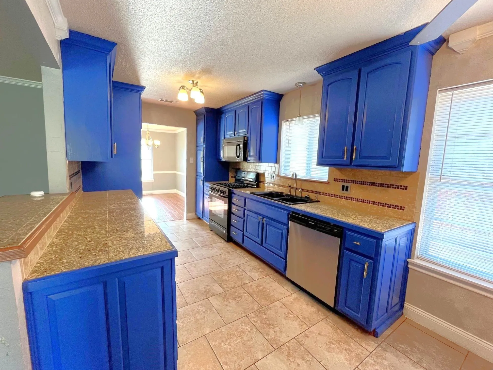 Kitchen featuring blue cabinetry, stone-finish countertops, tile flooring, and a tile backsplash