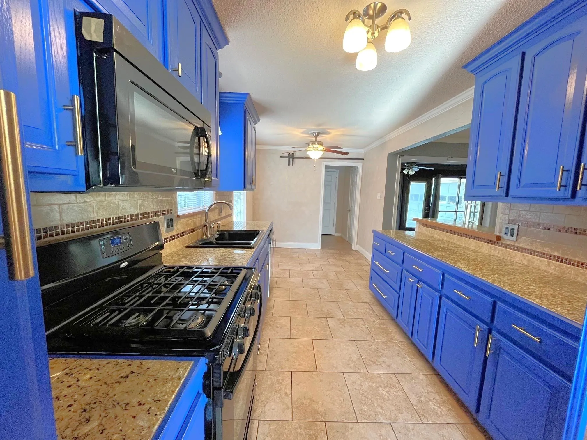 Kitchen featuring blue cabinetry, stone-finish countertops, tile flooring, and a tile backsplash