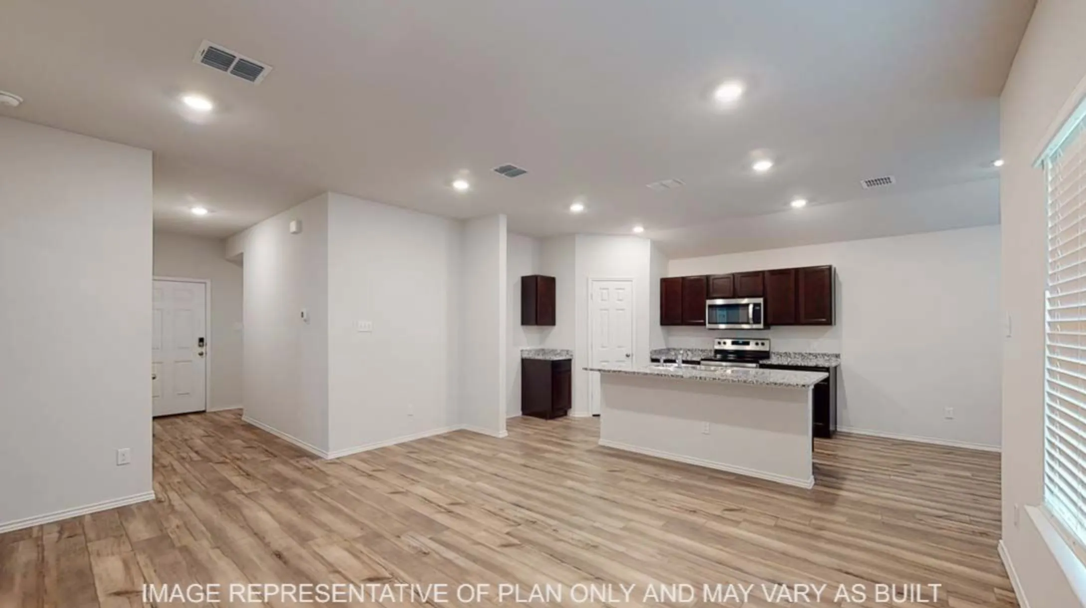 Open-concept living space with wood-finish flooring, recessed lighting, and a kitchen island featuring a light-toned countertop