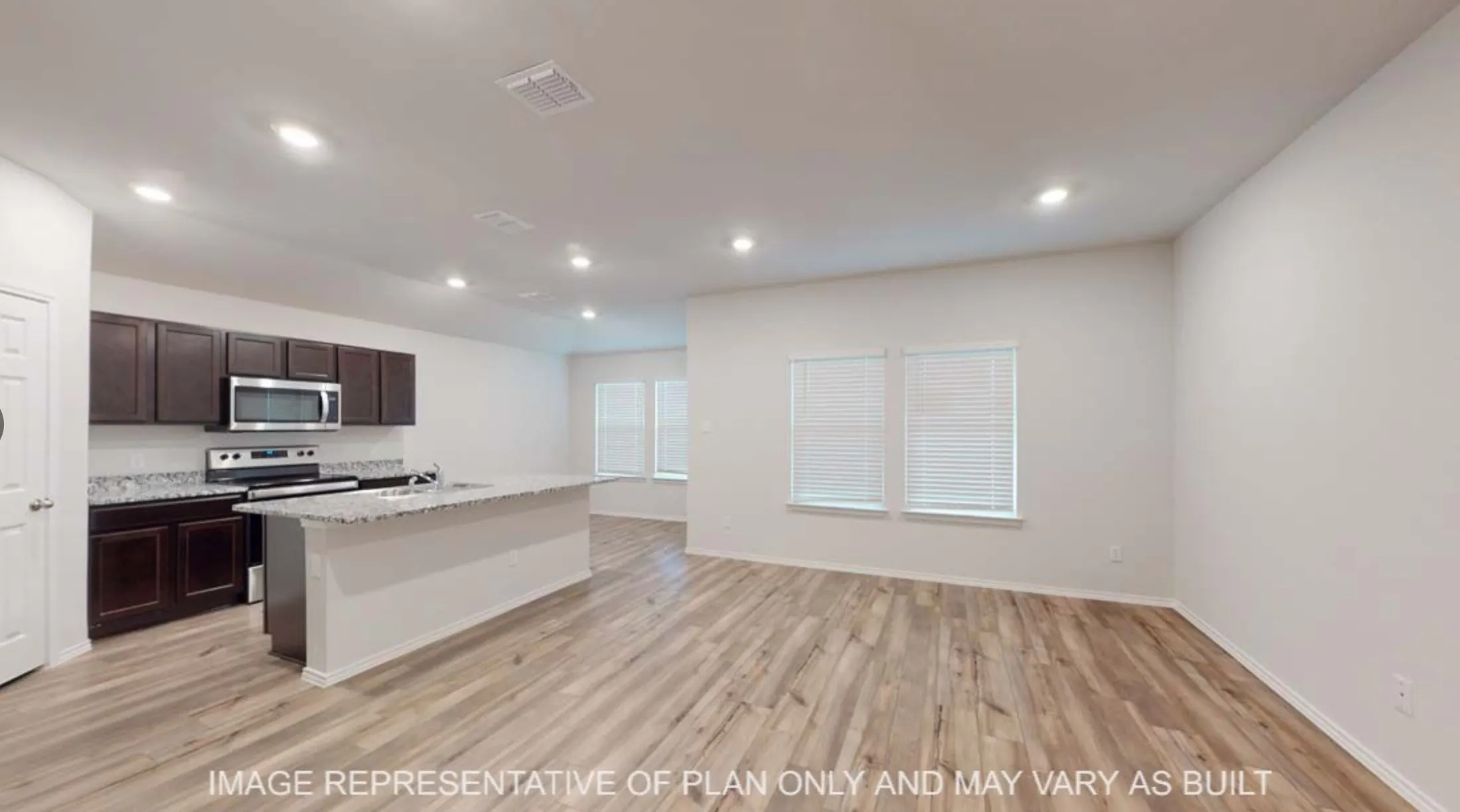 Open-concept living space with wood-finish flooring, recessed lighting, and multiple windows