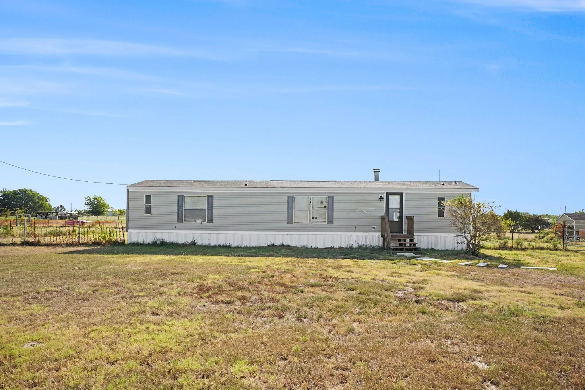 Single-story residence featuring siding exterior, a front entry with wooden steps, and a fenced perimeter