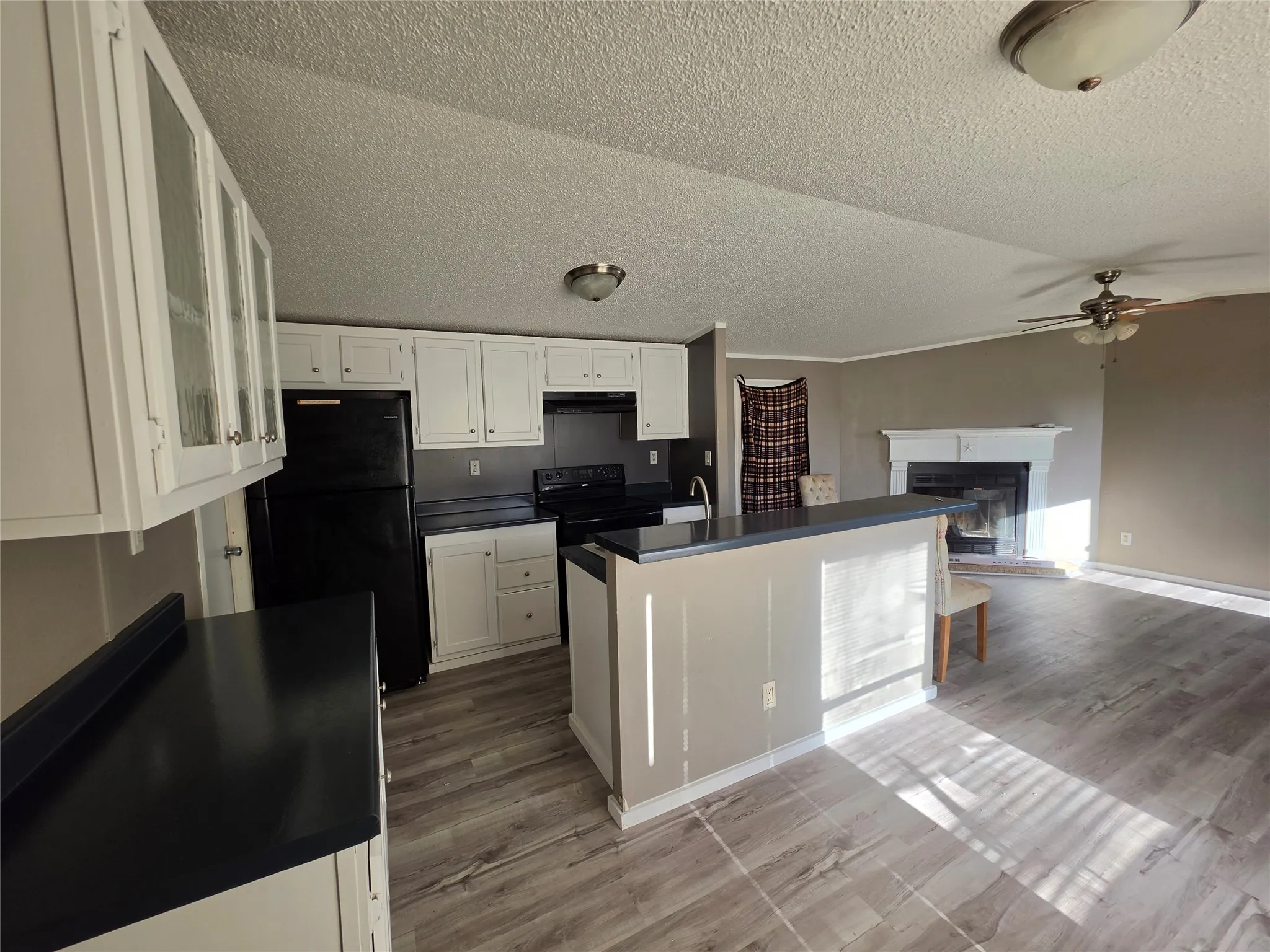 Kitchen with white cabinetry, dark countertops, and a peninsula