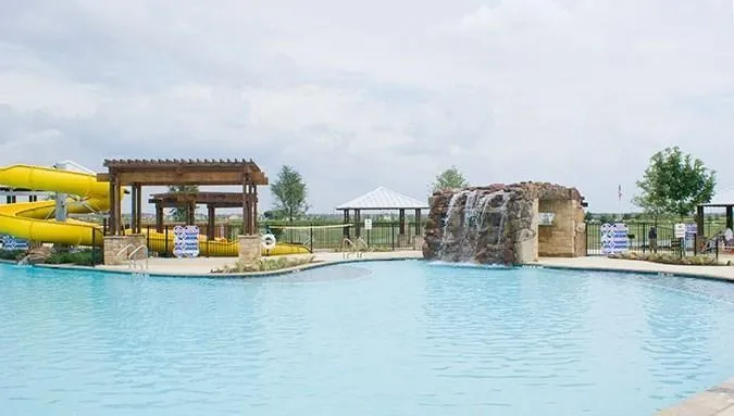 Community pool featuring a rock waterfall, shaded pergolas, and waterslides