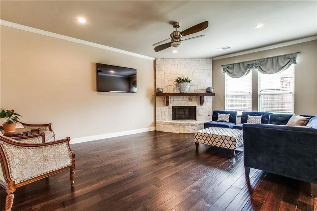 Hardwood flooring, recessed lighting, crown molding, stone fireplace, and a ceiling fan