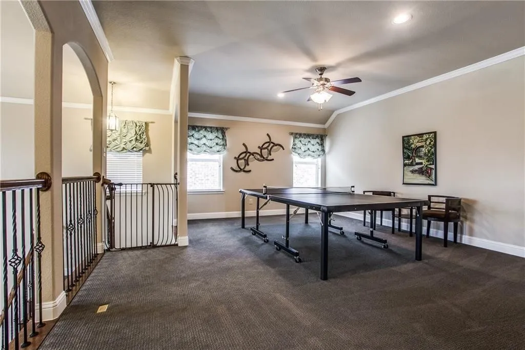 Carpeted bonus room with a ceiling fan, recessed lighting, arched doorway, and wrought iron railing