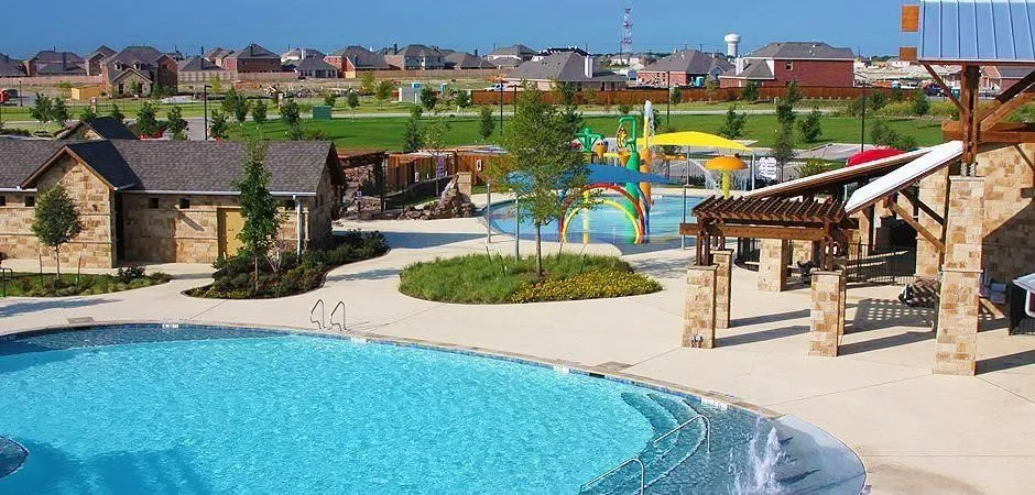 Resort-style pool with integrated steps, water features, and an adjacent children's splash pad