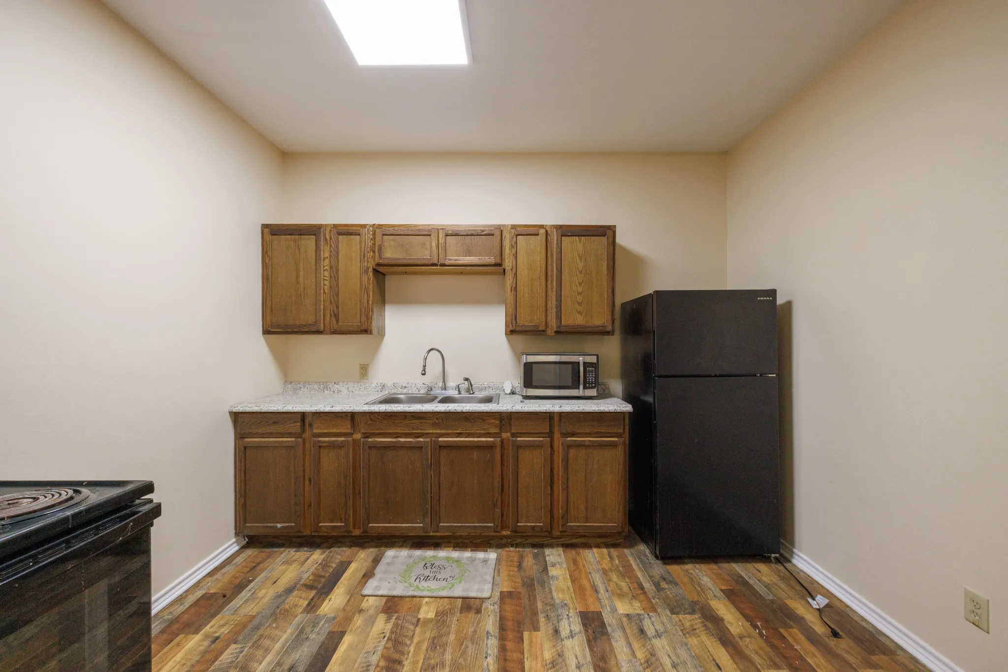 Full-size refrigerator, wood-finish flooring, built-in cabinetry, dual basin sink, and ample countertop space