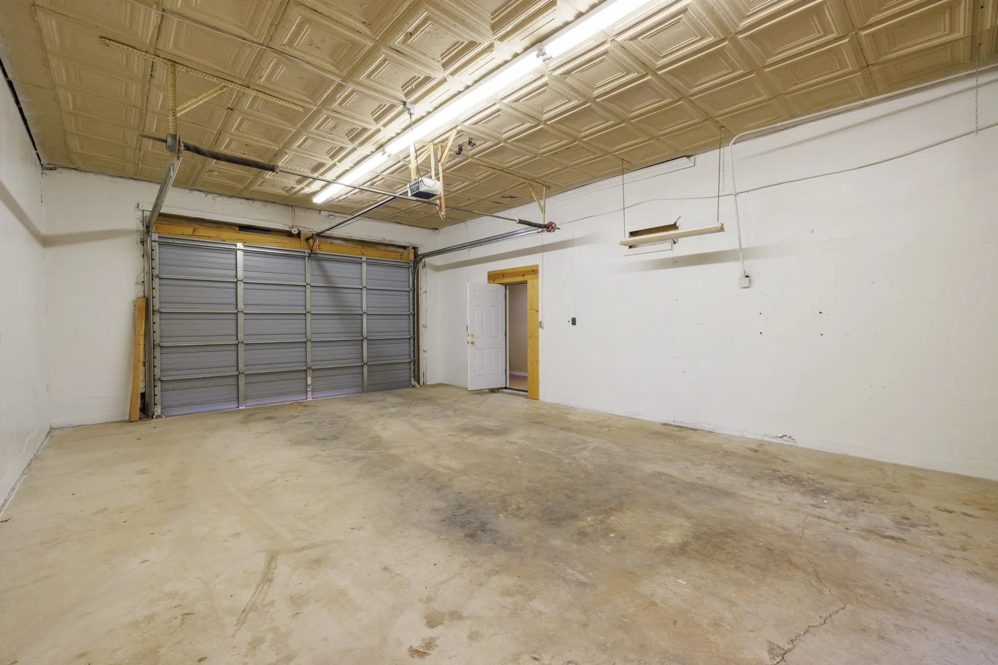 Spacious interior with a roll-up garage door, concrete flooring, and an embossed ceiling