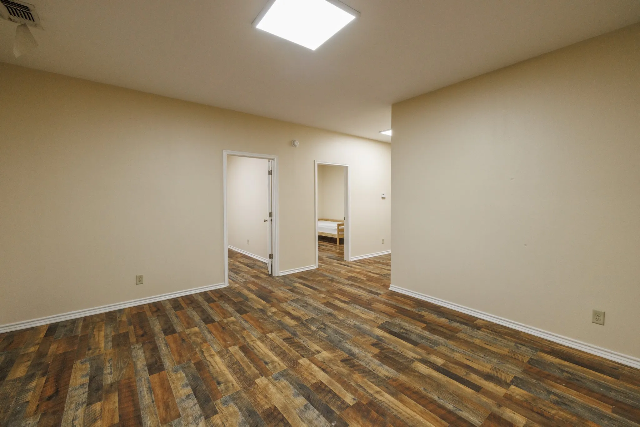 Wood-finish flooring throughout, neutral wall tones, and recessed square lighting