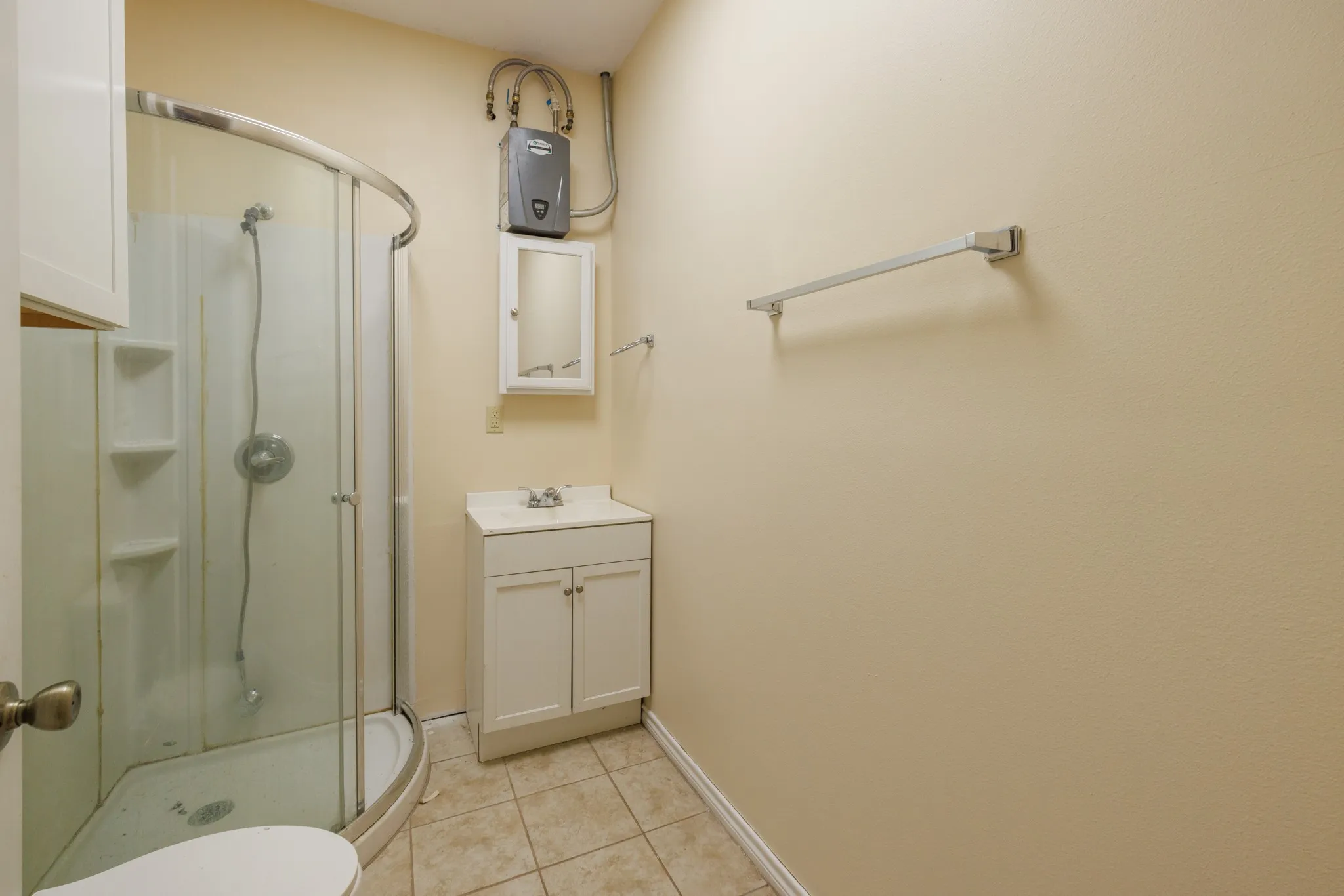 Enclosed shower with clear glass surround, single-sink vanity with white cabinetry, and wall-mounted mirrored medicine cabinet