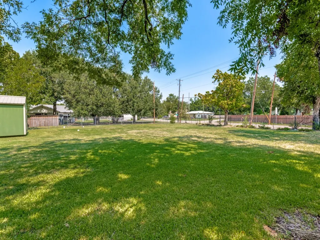 Expansive level grounds featuring mature shade trees, open lawn space, fenced perimeter and shed