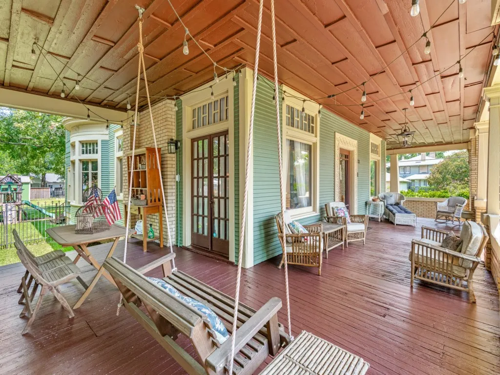 Expansive covered porch featuring wood-finish decking and multiple seating areas