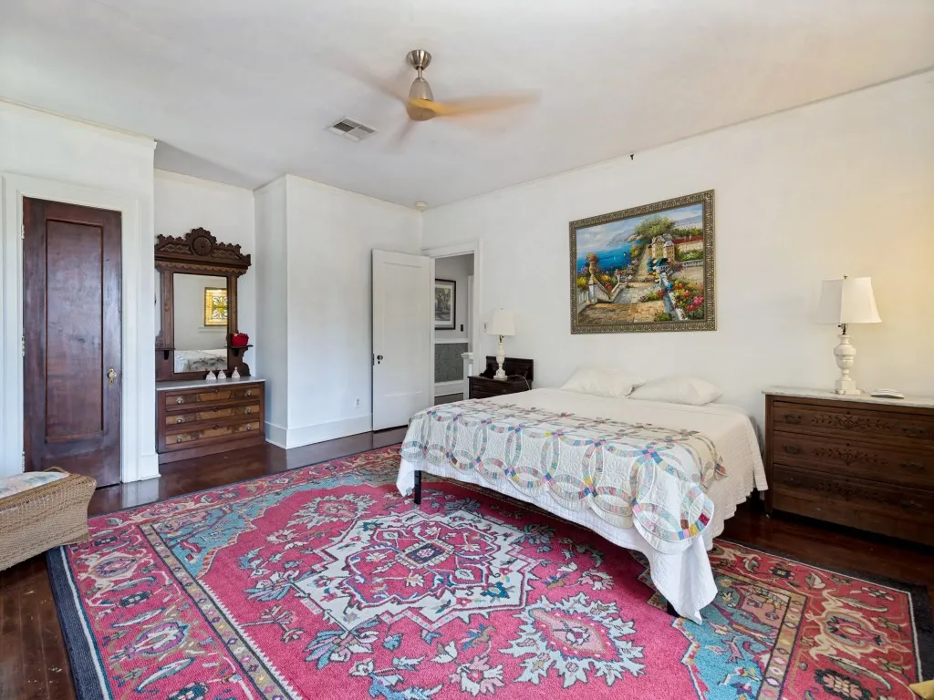 Spacious bedroom featuring hardwood flooring, a ceiling fan, and rich wood furnishings