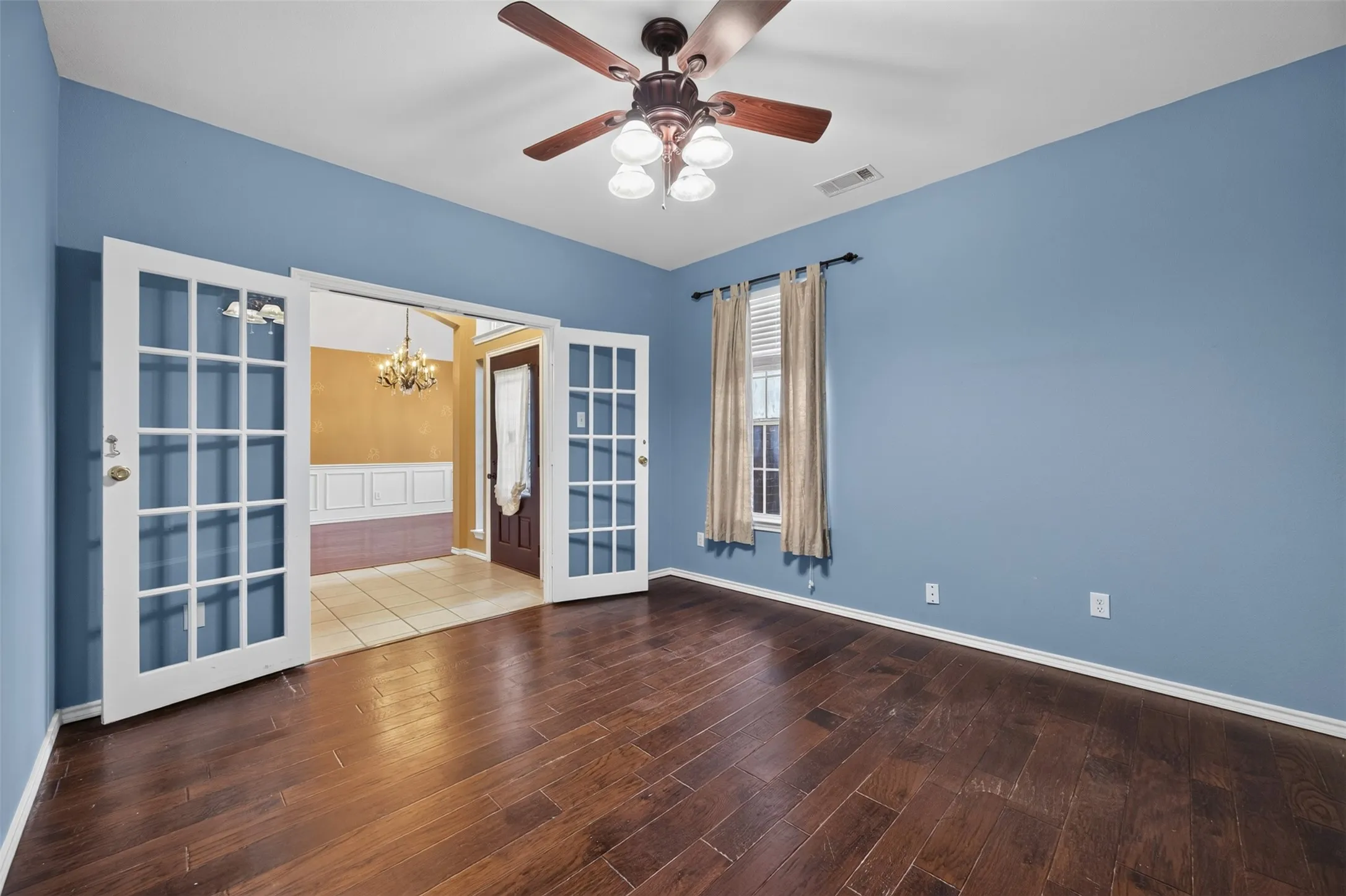 Wood-finish flooring, vaulted ceiling, ceiling fan, and French doors leading to an adjacent room