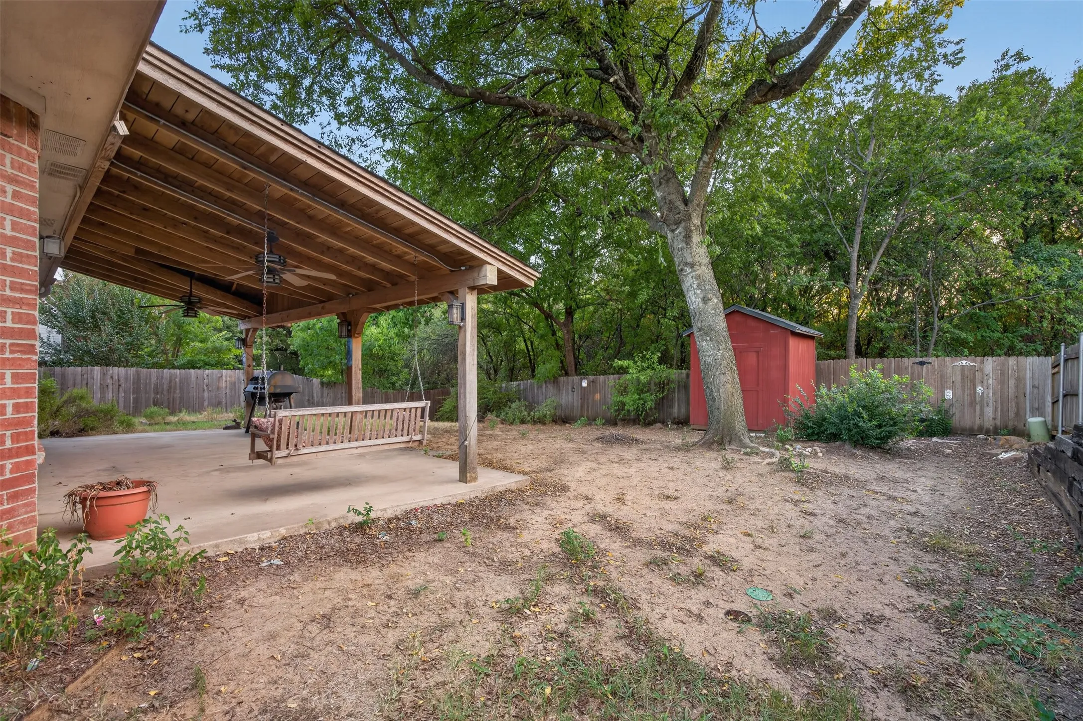 Covered patio featuring a wood ceiling and dual ceiling fans