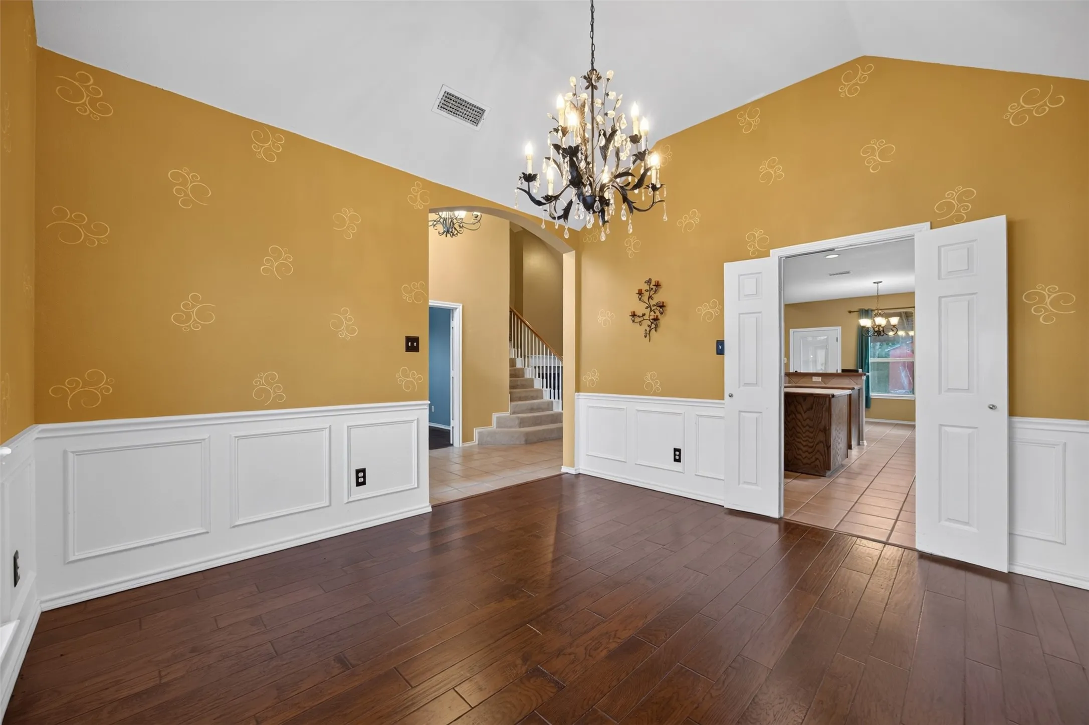 Hardwood-finish flooring, wainscoting, vaulted ceilings, and a decorative chandelier