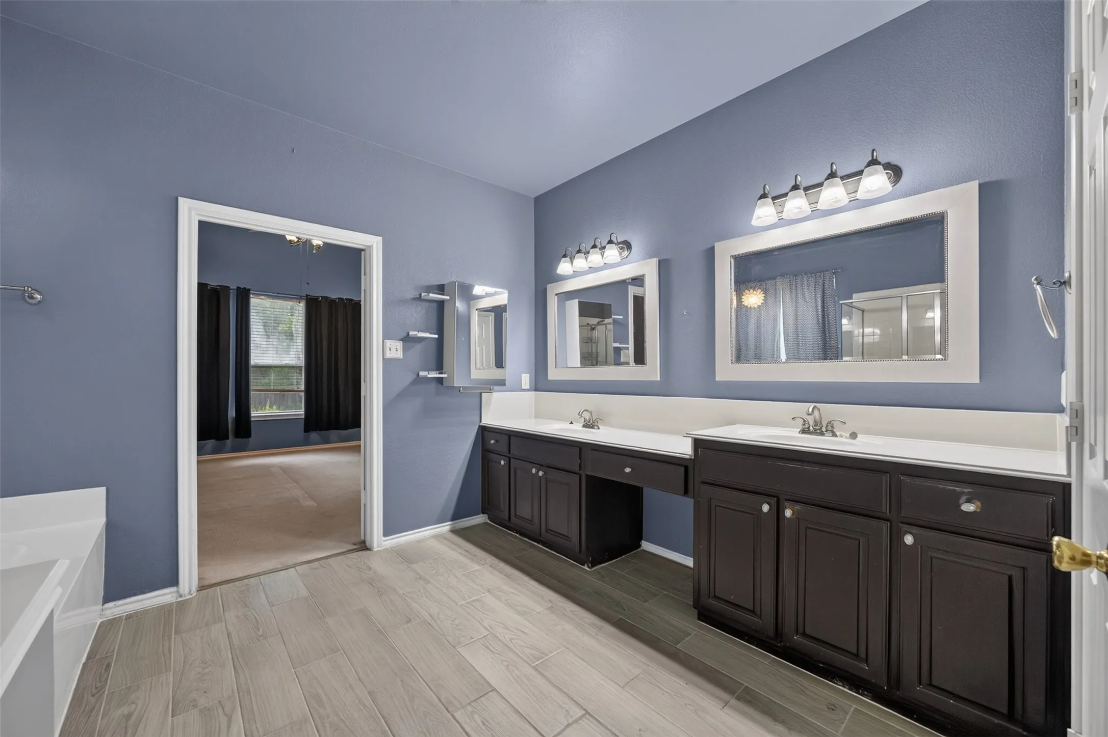 Dual vanity with dark wood-finish cabinetry, white countertops, and framed mirrors