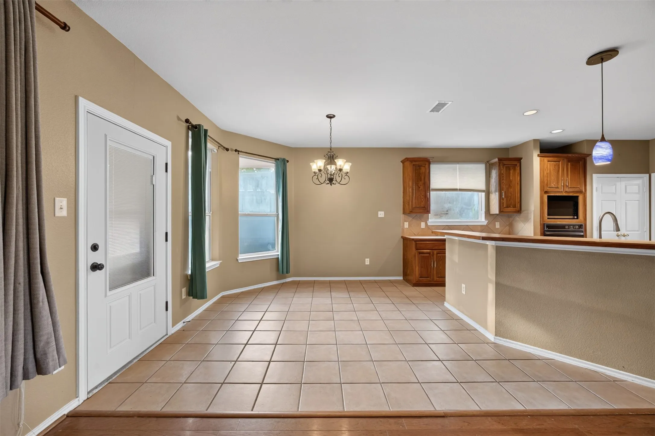Tile flooring, built-in cabinetry, recessed lighting, pendant lighting, and a glass-paneled door