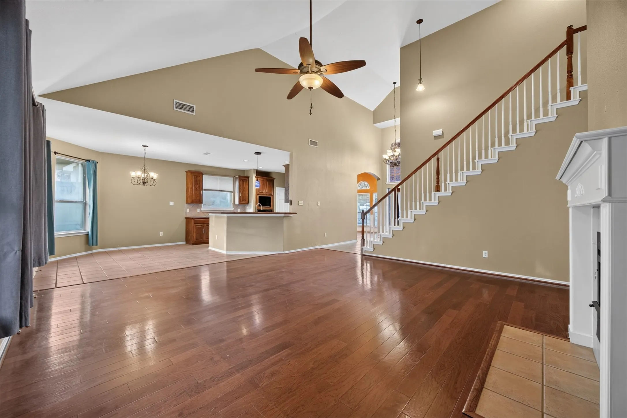 Vaulted ceilings, wood-finish flooring, staircase with white spindles, fireplace with mantel, and built-in kitchen cabinetry
