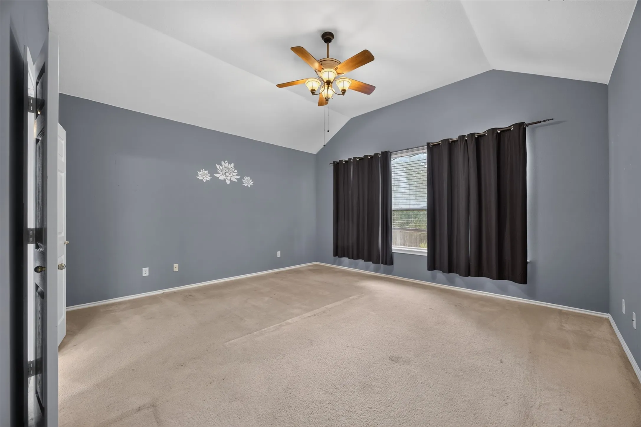 Vaulted ceiling with a wood-finish ceiling fan, neutral carpet flooring, and window with blinds