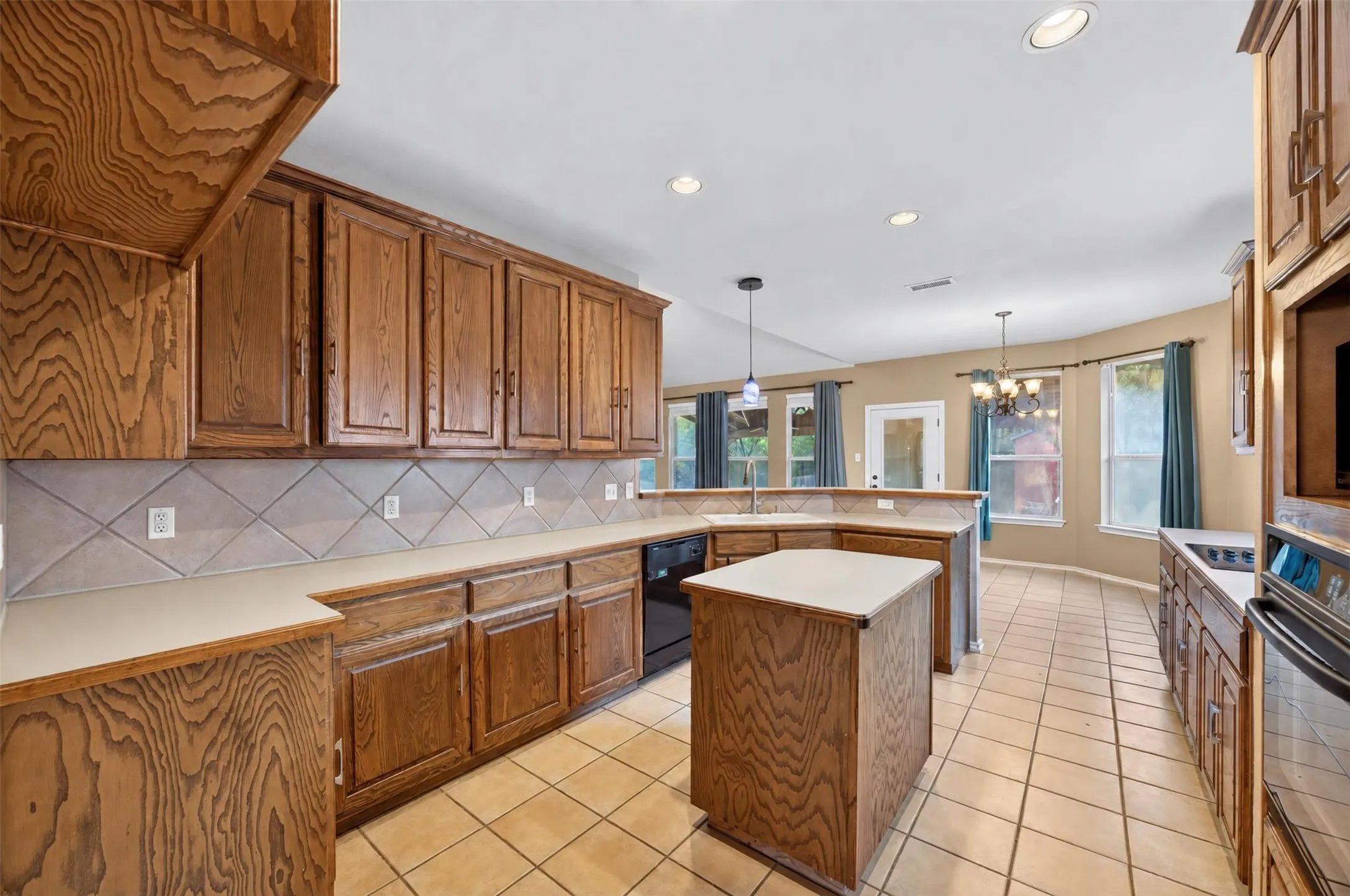 Kitchen featuring wood cabinetry, light-colored countertops, tile backsplash, and recessed lighting