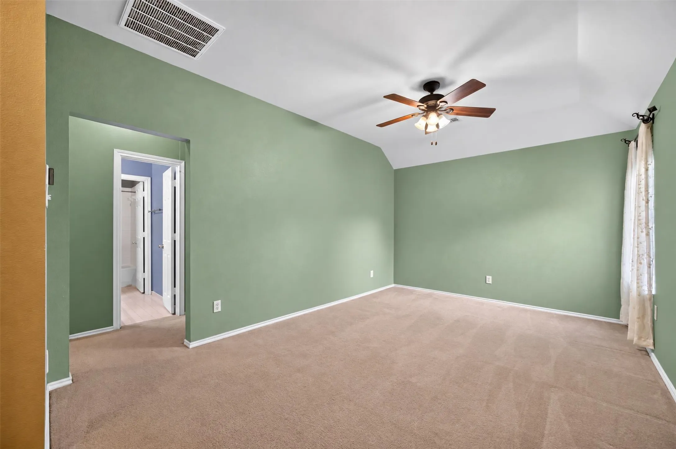 Carpeted room with a vaulted ceiling, ceiling fan, and painted walls