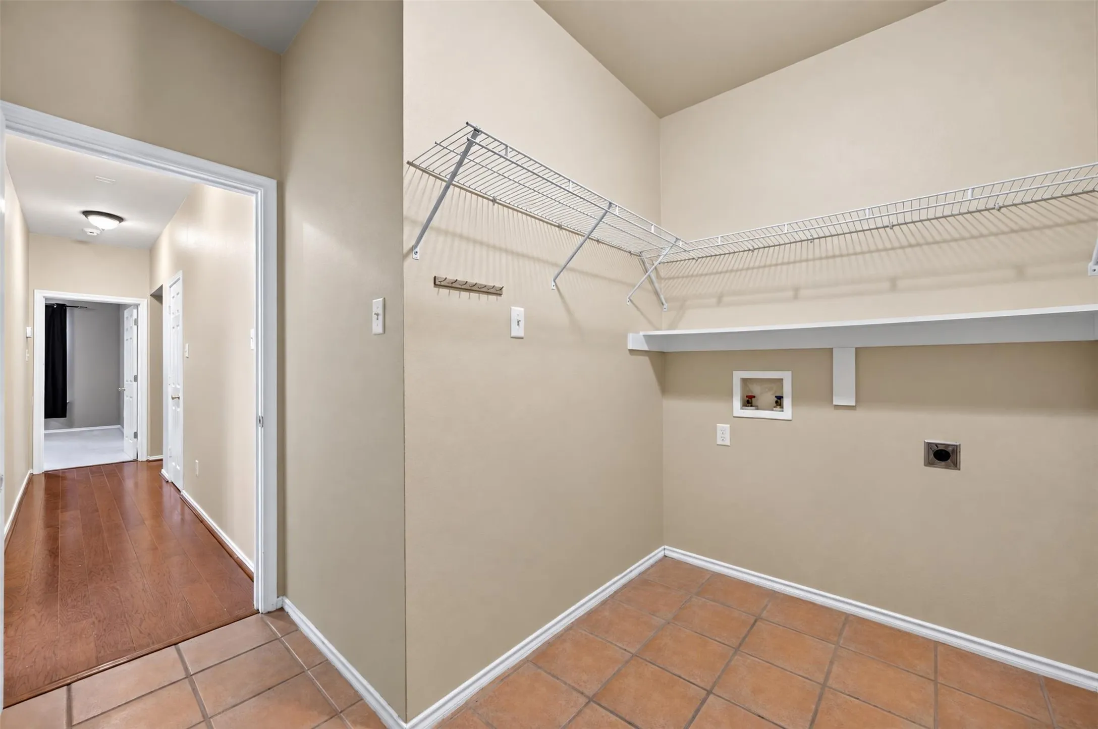 Laundry area featuring tile flooring, wire shelving, and a built-in hanging rack