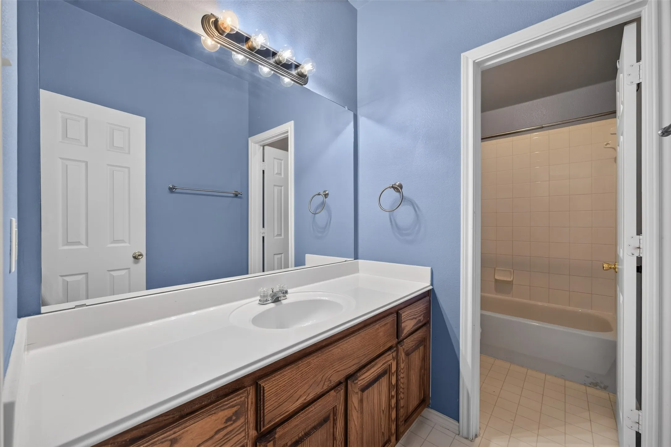 Vanity with wood-finish cabinetry, integrated sink, and a spacious countertop