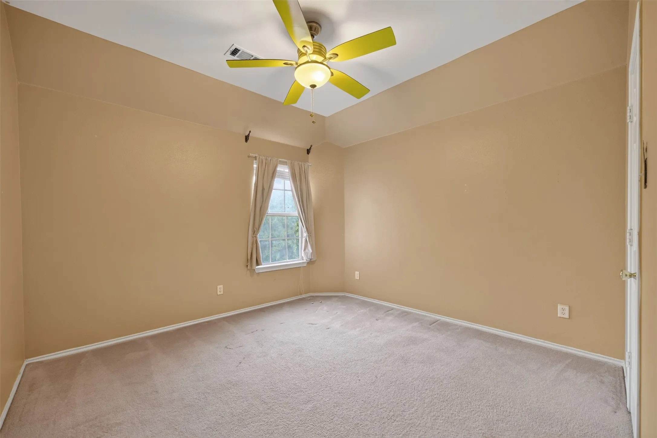 Carpeted room with a tray ceiling and a ceiling fan with light fixture
