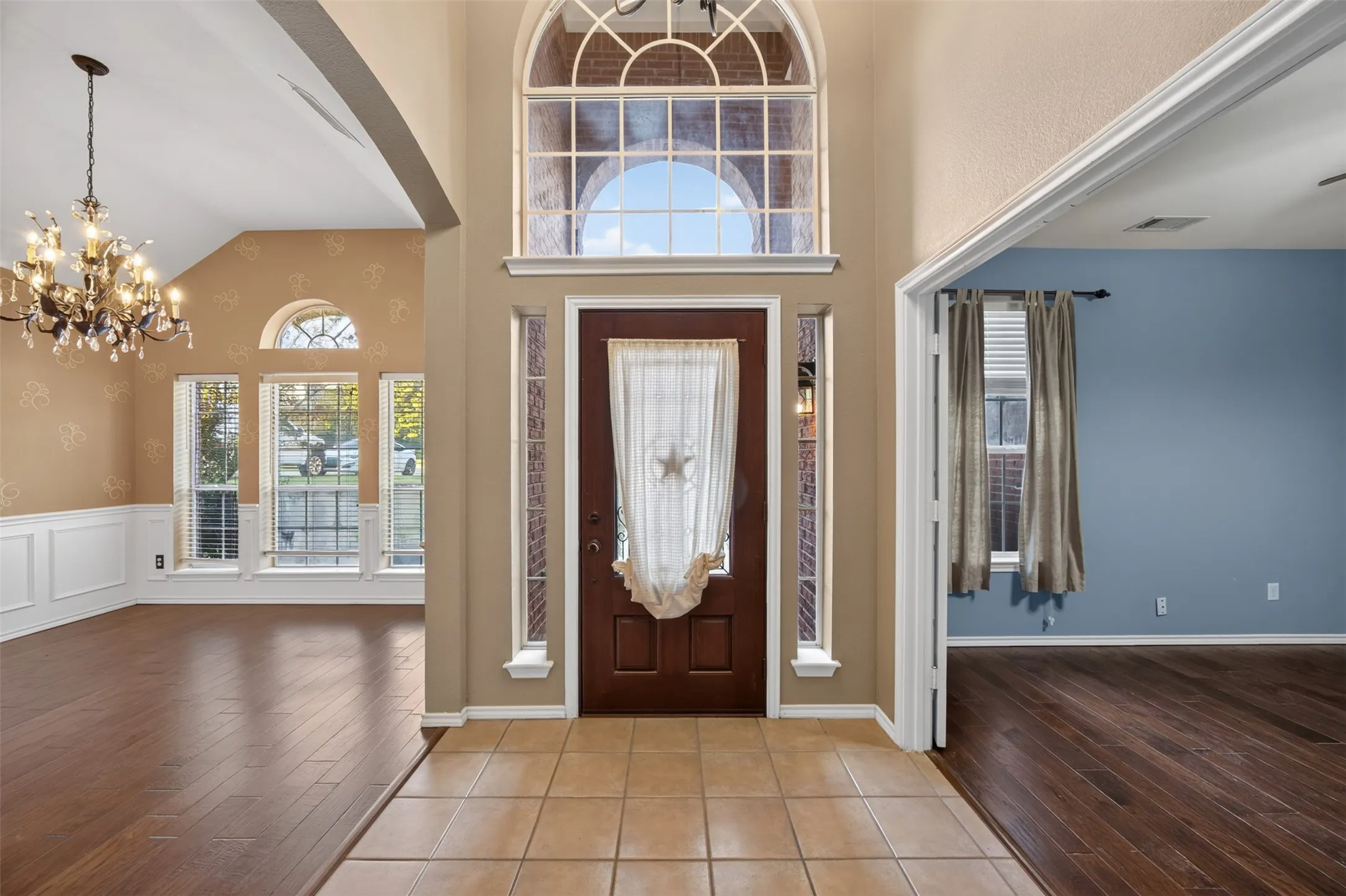 Foyer featuring a grand arched transom window, a dark wood-finish entry door, and tiled flooring