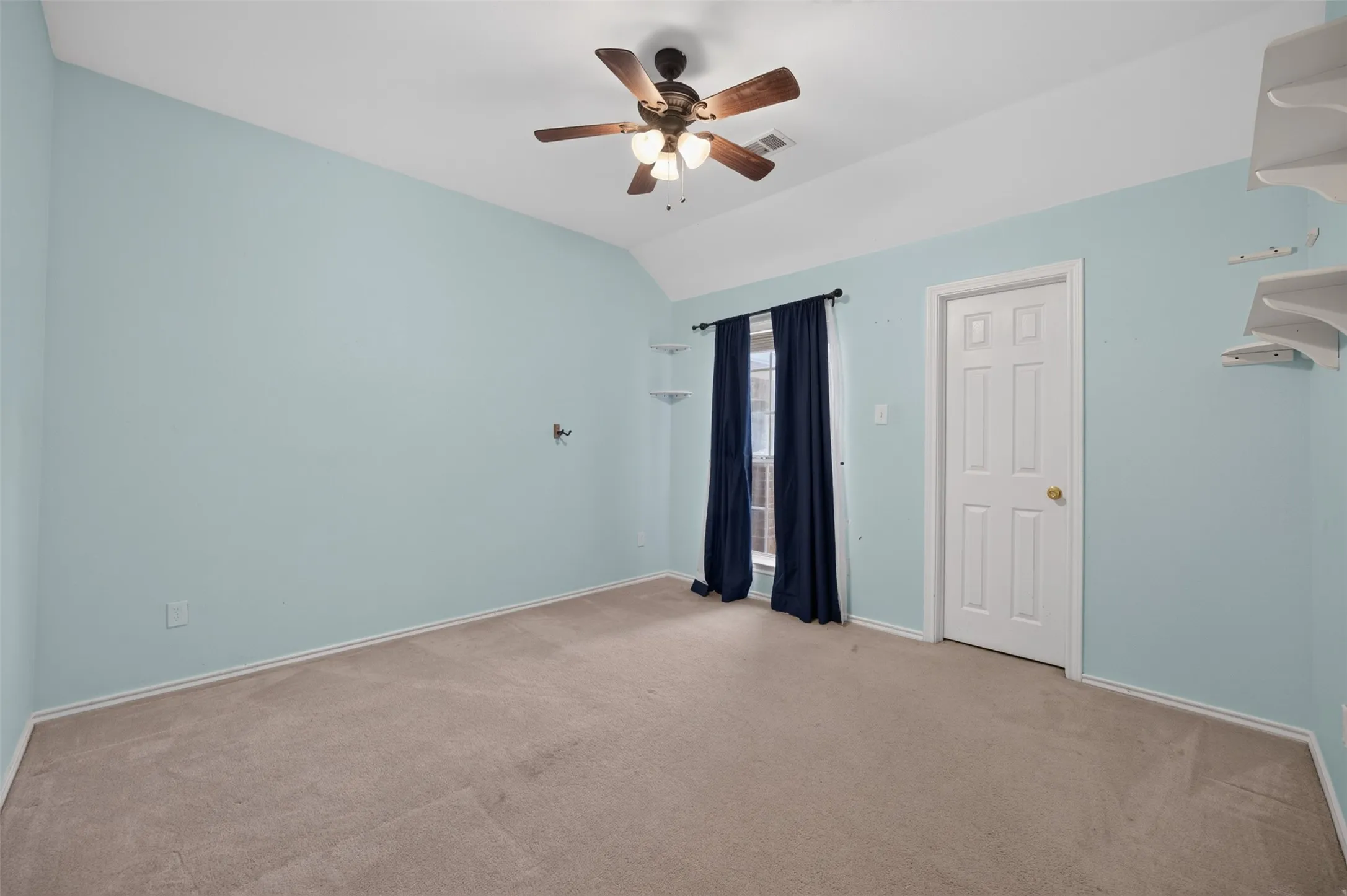 Vaulted ceiling with a ceiling fan, carpeted flooring, and a window with curtain rods