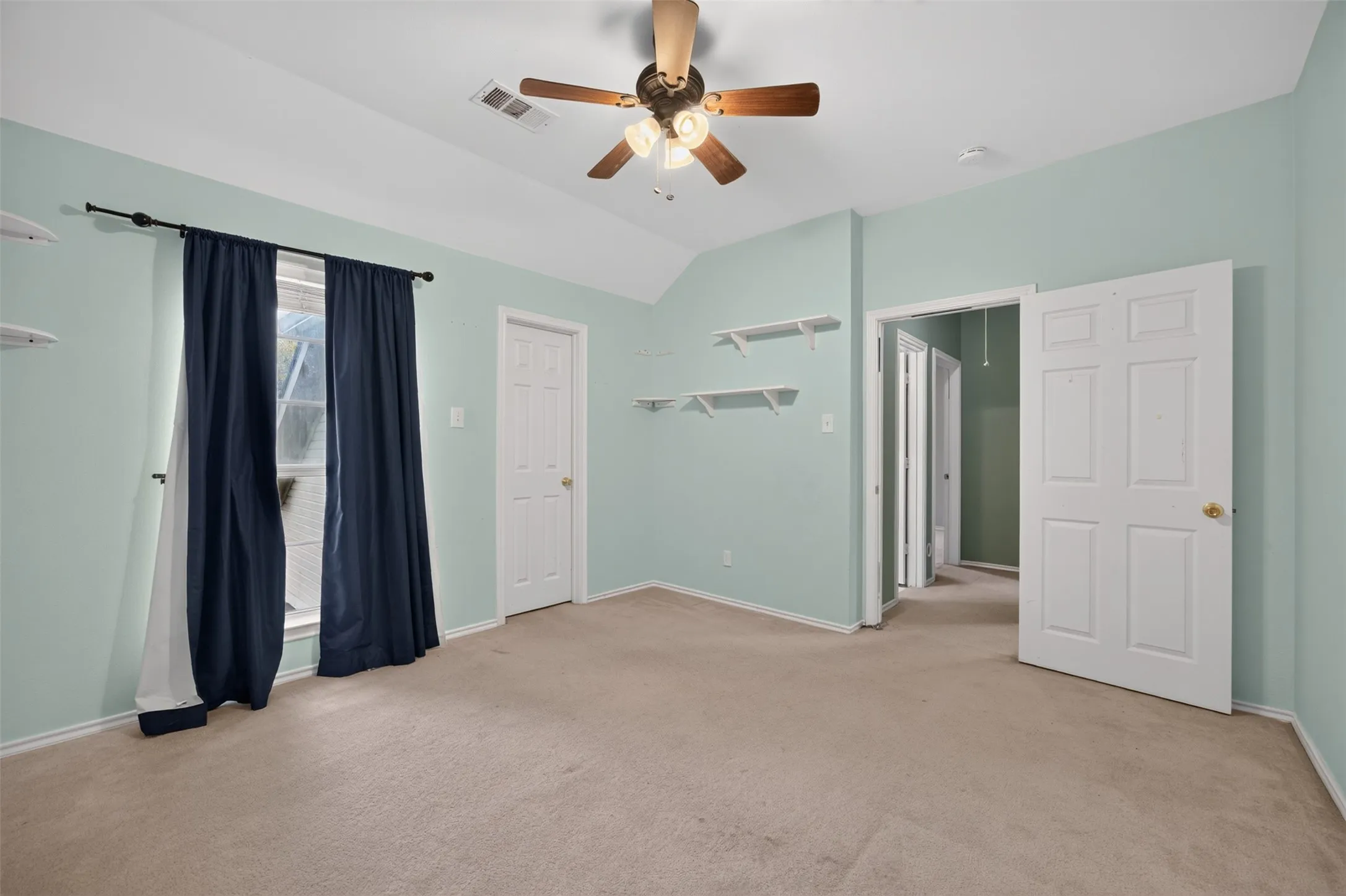 Carpeted flooring with a vaulted ceiling, ceiling fan, and built-in shelving