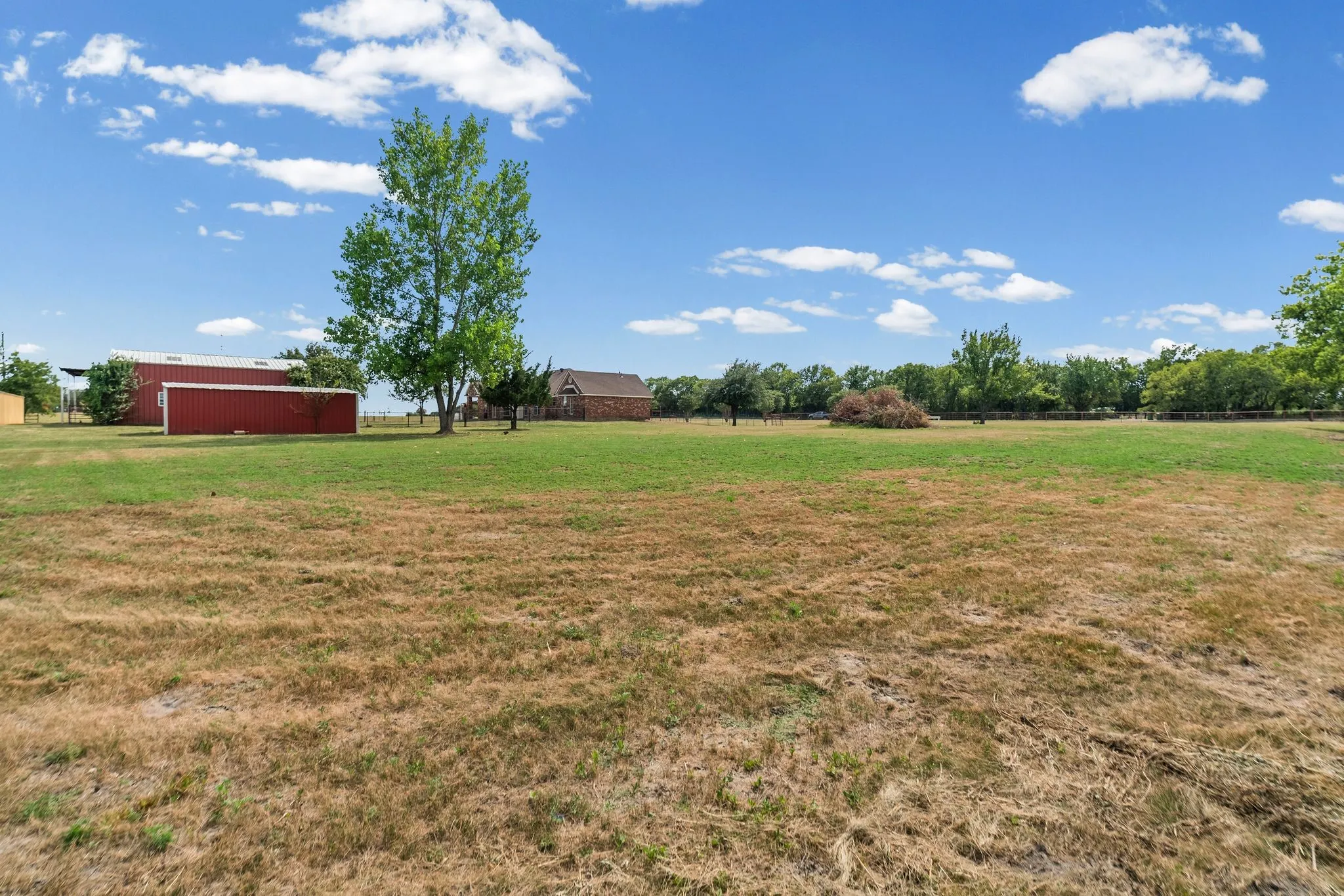 View of south pasture with 12 x 30 stable with 2-stalls + equipment room. Beyond that is the 30 x 40 shop and the house.