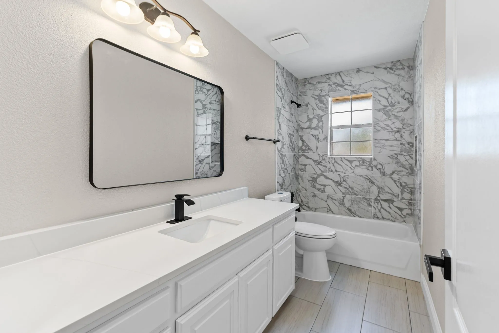 Secondary bathroom featuring a wide vanity with a white countertop, under-mount sink, and matte black faucet