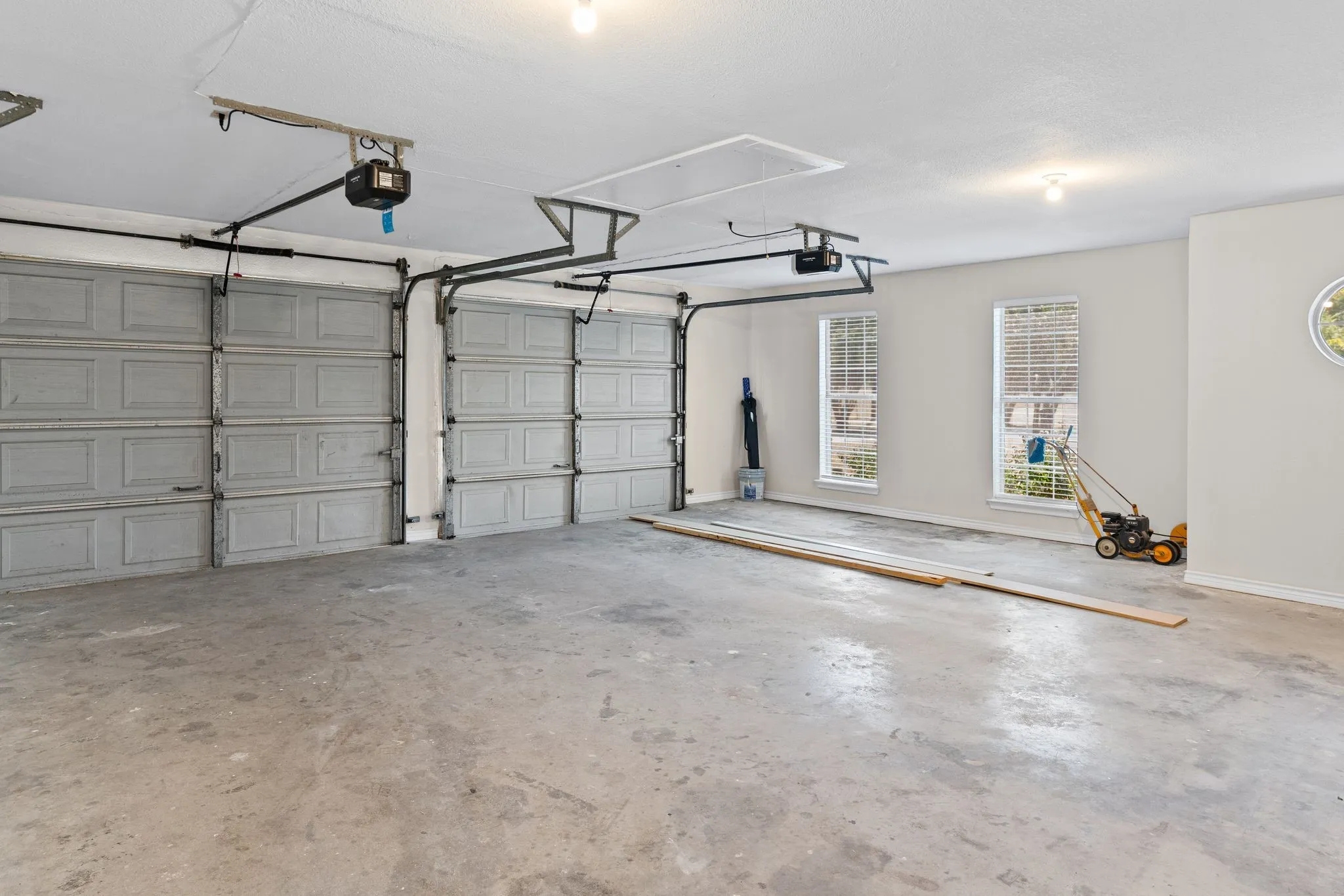 Attached two-car garage featuring a concrete floor, two windows, and an overhead access panel