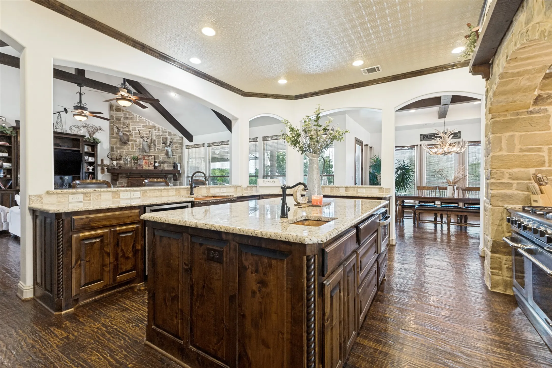 Kitchen featuring a large island with an undermount sink, stone countertops, and wood-finish flooring
